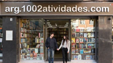 Casal jovem; um rapaz e uma moça de mãos dadas de frente a uma livraria do site arg.1002atividades.com